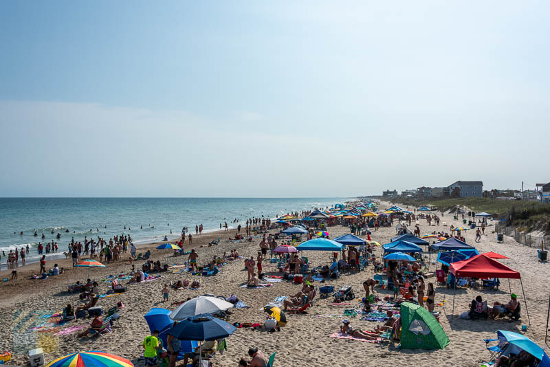 Canopies, umbrellas and lots of beachgoers next to Bogue Inlet Fishing Pier