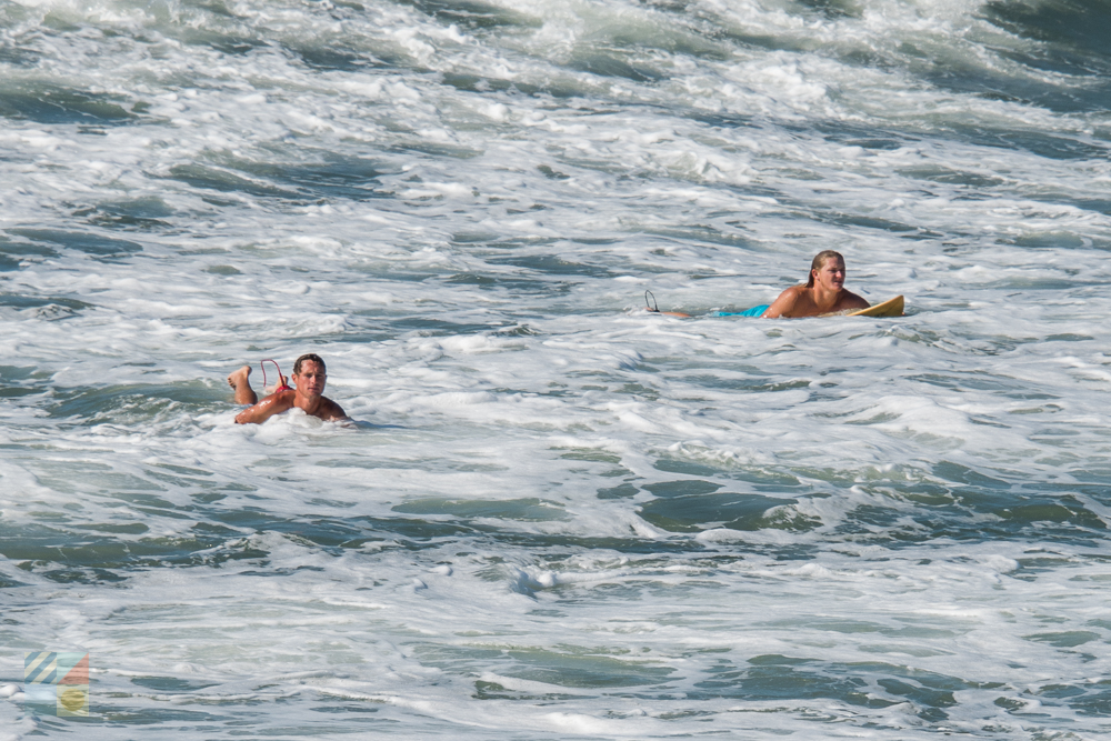 Surfers paddle out along a Crystal Coast beach